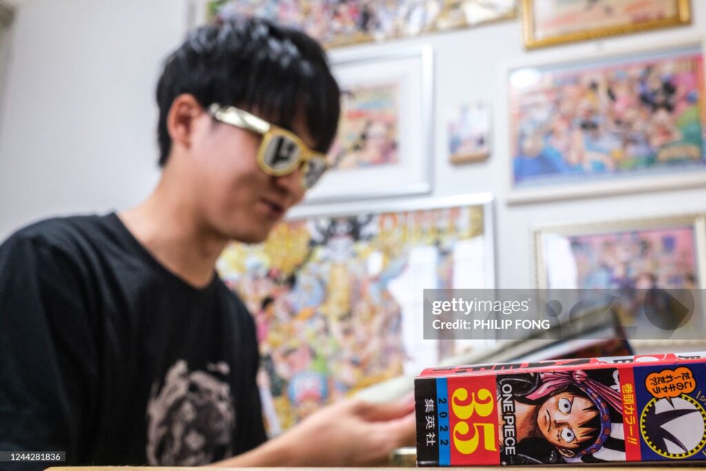JAPAN-ENTERTAINMENT-CULTURE-MANGA-ONEPIECEIn this picture taken on September 11, 2022, fan of Japanese manga series "One Piece" who goes by the online moniker Arimo reads the comic on Weekly Shonen Jump magazine in his home in Kamisu, Ibaraki Prefecture. - The Japanese comic-book saga "One Piece" began 25 years ago and is one of the biggest-selling mangas of all time with more than 500 million copies sold globally. - TO GO WITH Japan-entertainment-culture-manga-OnePiece, FEATURE by Tomohiro OSAKI (Photo by Philip FONG / AFP) / TO GO WITH Japan-entertainment-culture-manga-OnePiece, FEATURE by Tomohiro OSAKI (Photo by PHILIP FONG/AFP via Getty Images)