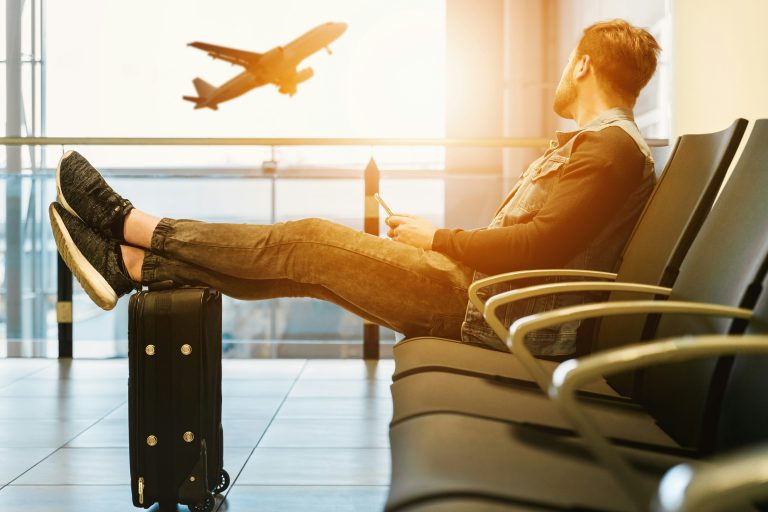 travel agent: man relaxing at airport watching a plane take off