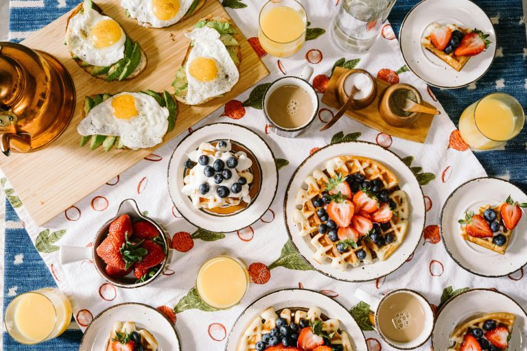 Breakfast table spread with waffles, toast, eggs, and fruit - vegan