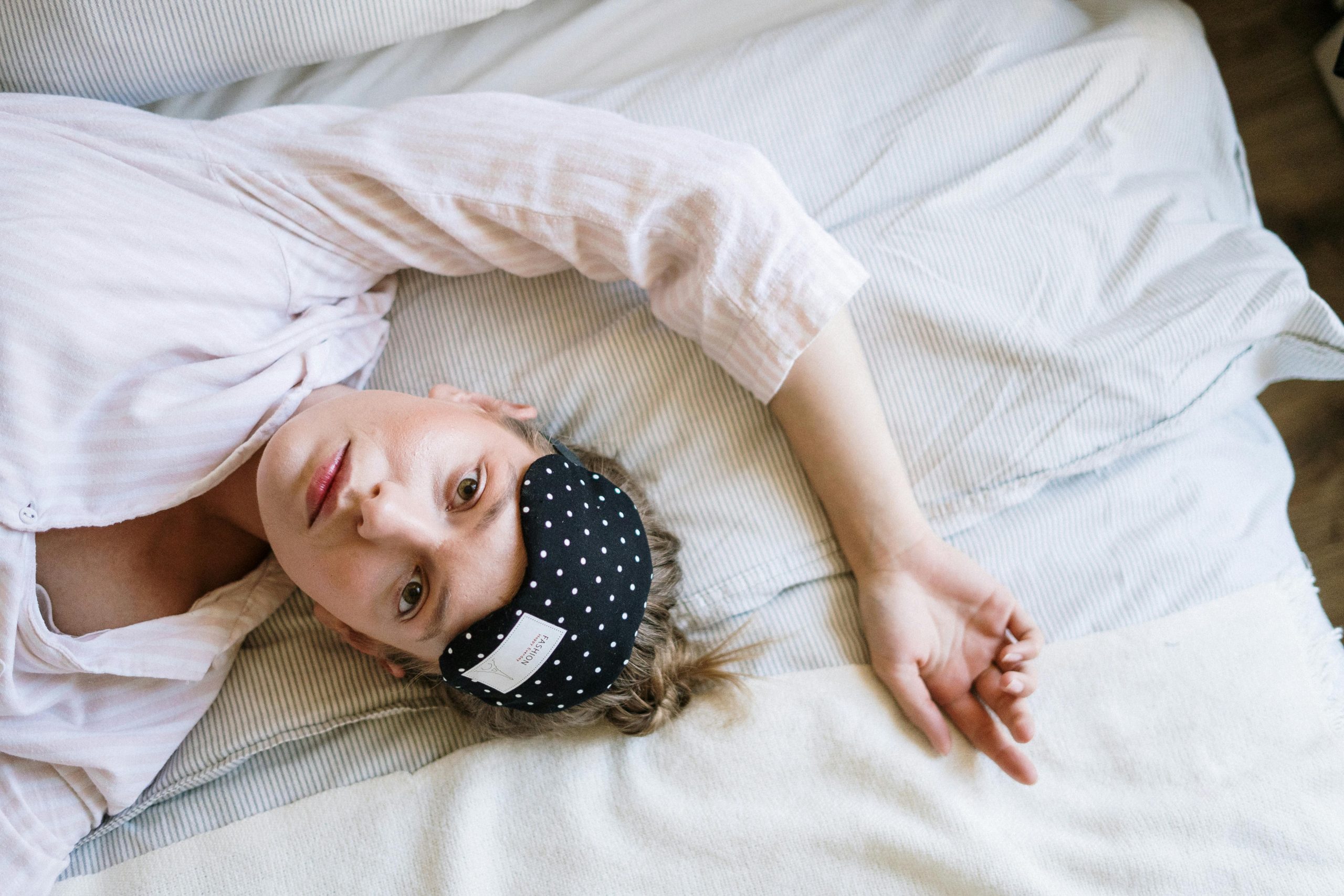 Sleep: woman wide awake in bed with eye mask pushed up on forehead