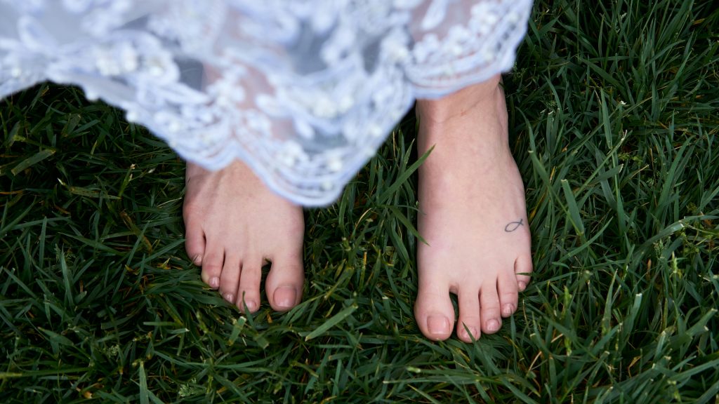 A woman's feet. Image courtesy of Unsplash.com. https://unsplash.com/photos/person-in-white-lace-skirt-on-green-grass-field-cd9y-nR3mMQ