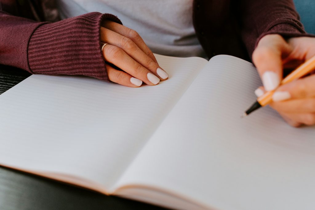 Person writing. Image courtesy of Unsplash.com. https://unsplash.com/photos/person-writing-on-white-paper-xcvXS6wDCAY