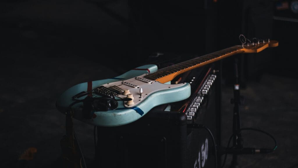 A guitar laying on a speaker. Image courtesy of Unplash.com. https://unsplash.com/photos/teal-and-brown-electric-guitar-phS37wg8cQg