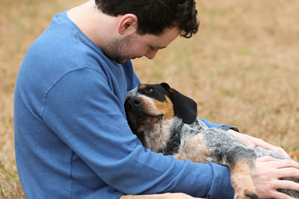 Man with dog. He may be teaching him to play fetch. Photo by Cynthia Smith on Unsplash. https://unsplash.com/photos/man-in-blue-shirt-hugging-black-and-white-short-coated-dog-mWoEDIeWQWc