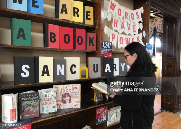 A woman reading one of many frequently banned books at a library that refuses to ban books.