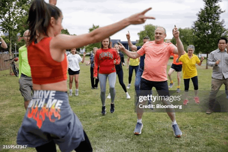 A Zumba instructor leading a class outdoors in a green field.