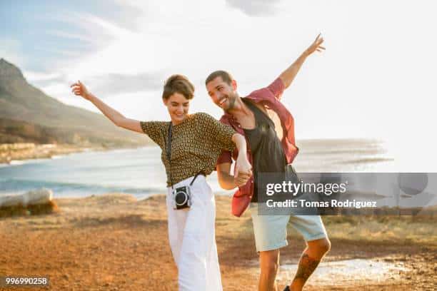 Happy cheerful couple hand in hand at the coast at sunset- marriage