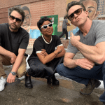 Rob McElhenney, Charlie Day, and Quinta Brunson posing on the "Abbott Elementary" set.