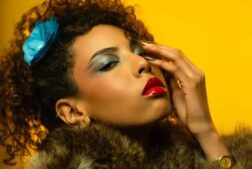 A woman wearing bright and bold makeup with a yellow background