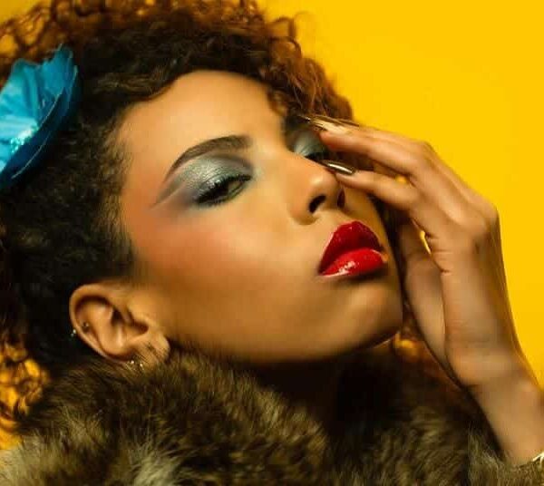 A woman wearing bright and bold makeup with a yellow background
