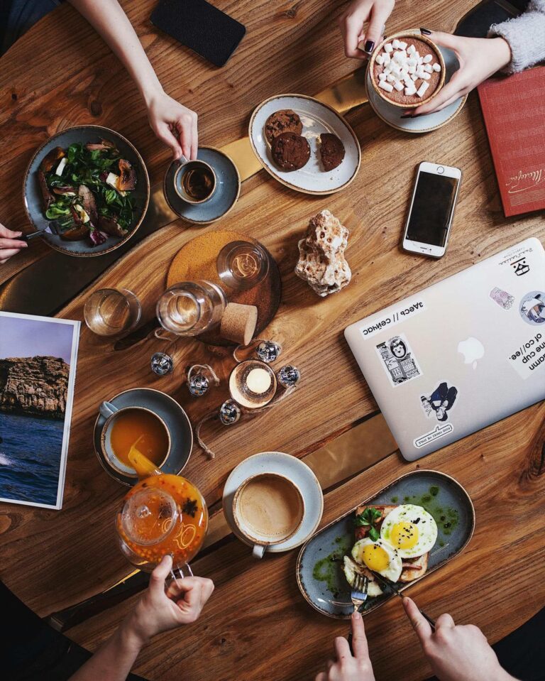 A group enjoying a diverse breakfast spread with coffee on a rustic wooden table. Perfect for food and lifestyle themes.