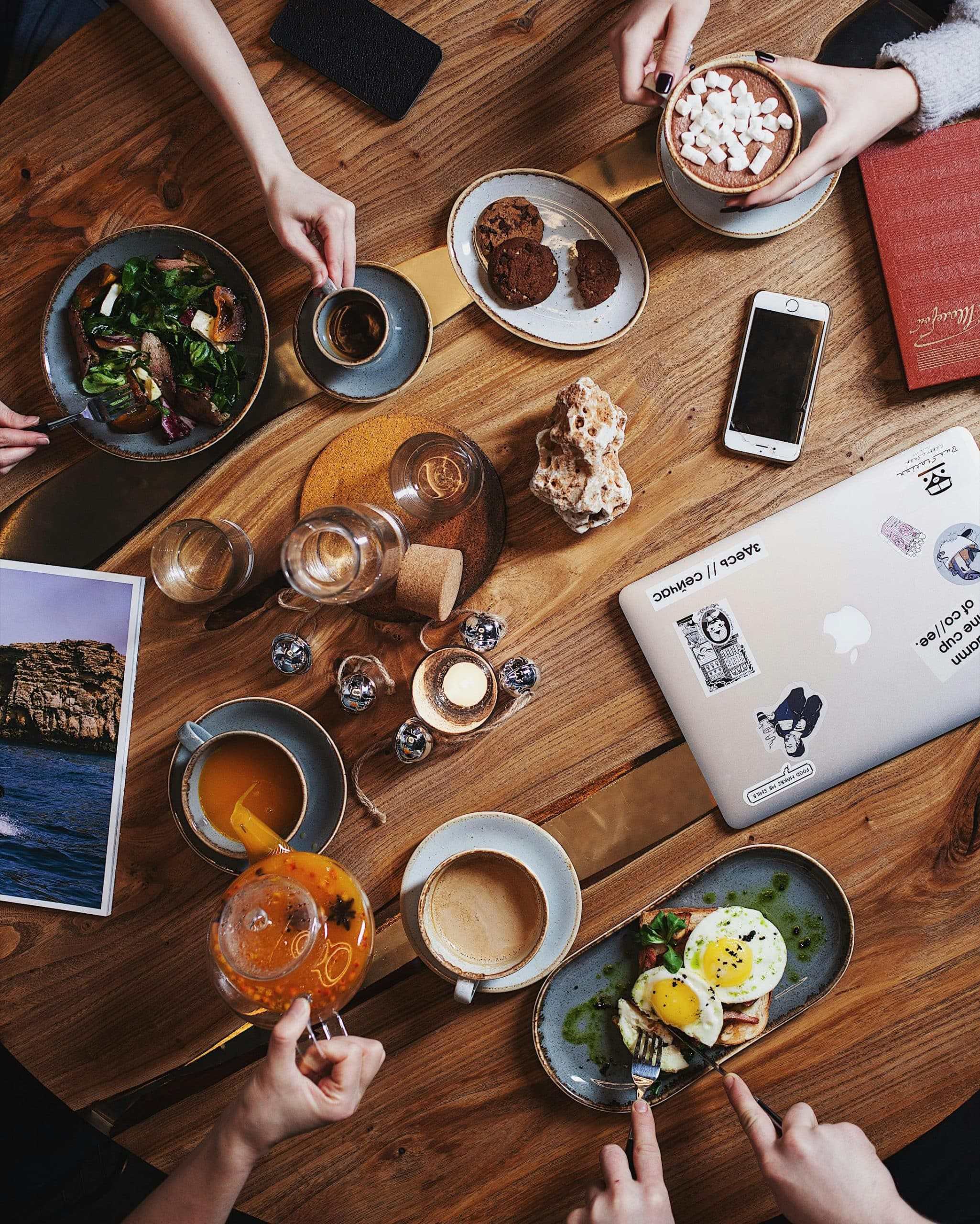A group enjoying a diverse breakfast spread with coffee on a rustic wooden table. Perfect for food and lifestyle themes.