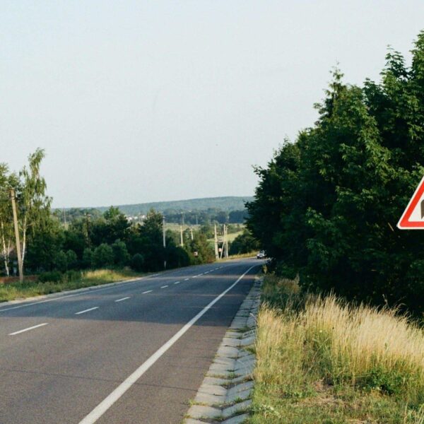 A red and white sign sitting on the side of the road. Detour Travel