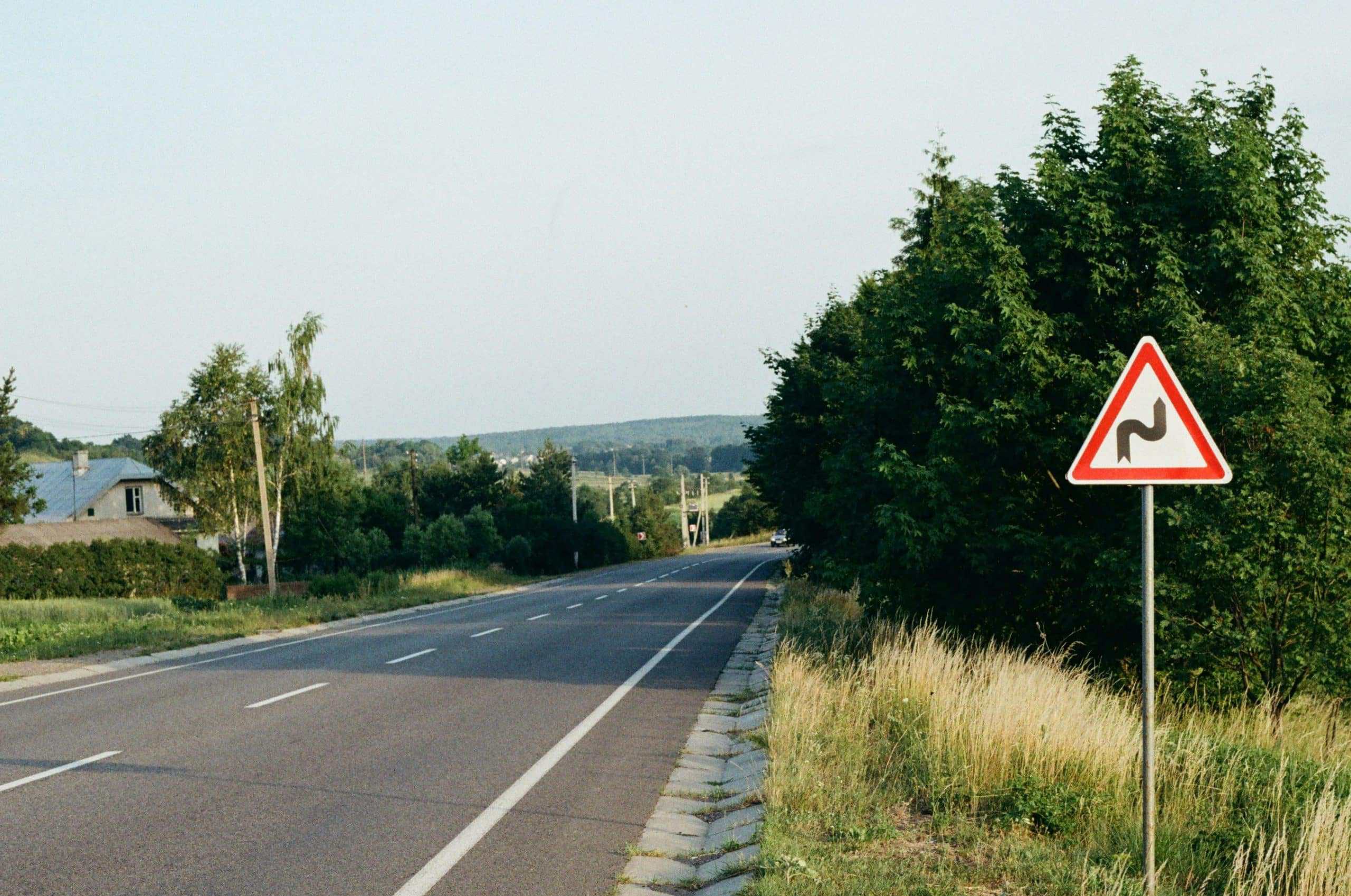 A red and white sign sitting on the side of the road. Detour Travel