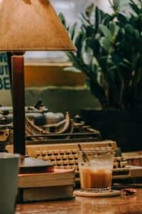A warm, vintage workspace featuring a typewriter and a cup of coffee on a wooden desk.