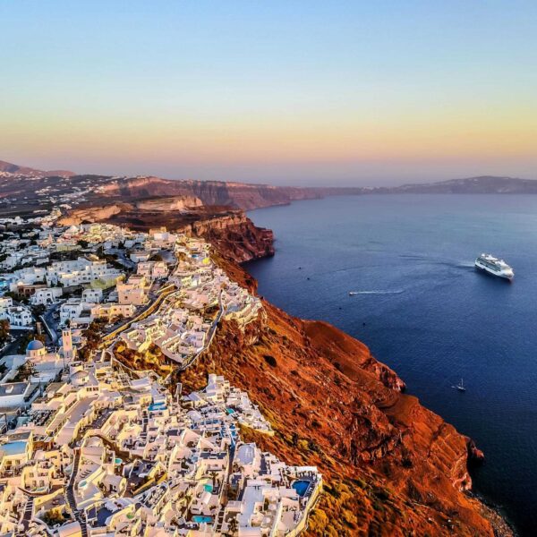 Stunning aerial shot of Santorini coast at sunset with a cruise ship in the Aegean Sea. Spiritual Getaway location