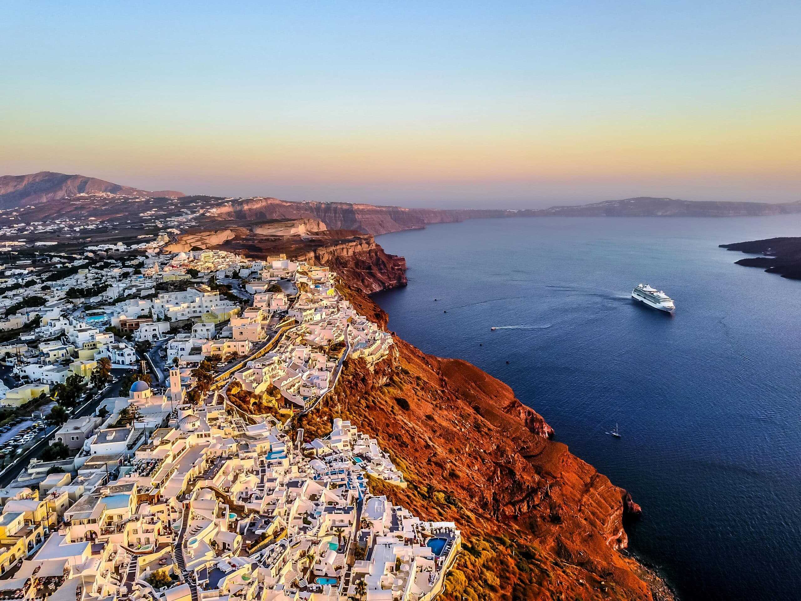 Stunning aerial shot of Santorini coast at sunset with a cruise ship in the Aegean Sea. Spiritual Getaway location
