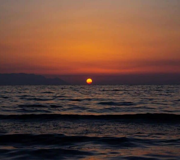 A breathtaking sunset over the ocean with a vibrant orange sky and gentle waves. summer solstice