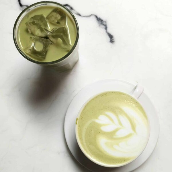 Elegant matcha latte with latte art and iced green tea on a marble table, perfect for tea enthusiasts.