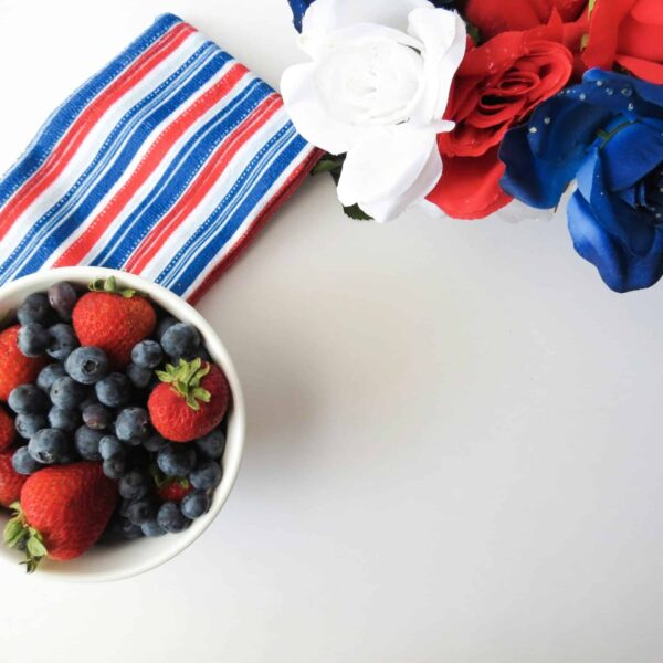 Charcuterie board featuring a bowl of strawberries and blueberries with American flag-themed decor, perfect for Fourth of July gatherings and festive charcuterie boards.