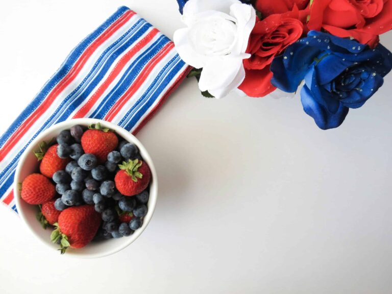 Charcuterie board featuring a bowl of strawberries and blueberries with American flag-themed decor, perfect for Fourth of July gatherings and festive charcuterie boards.