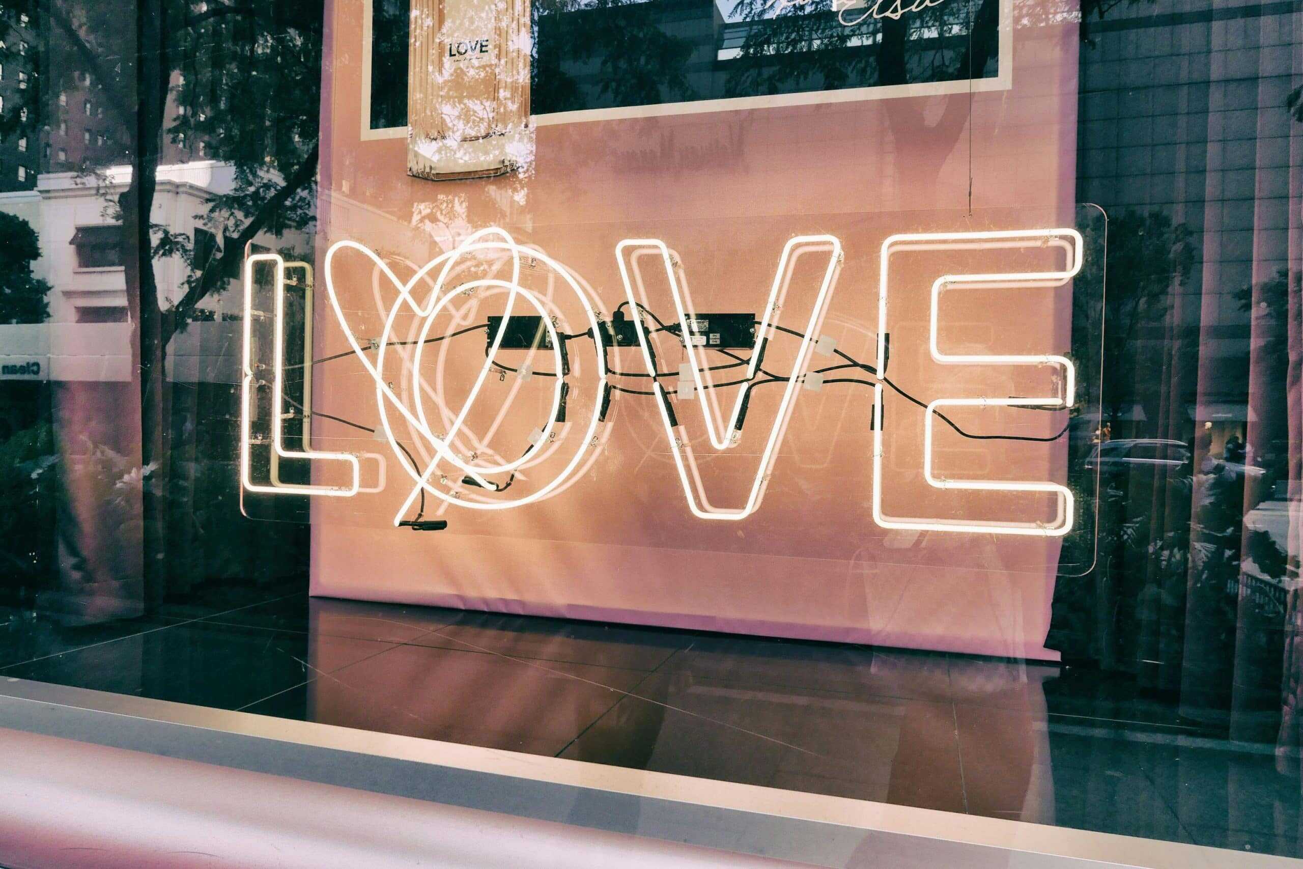 Neon 'LOVE' sign in a modern urban window display with reflections—symbolizing how modern love languages expresses visually in today’s digital culture. Photo by Loe Moshkovska via Pexels.