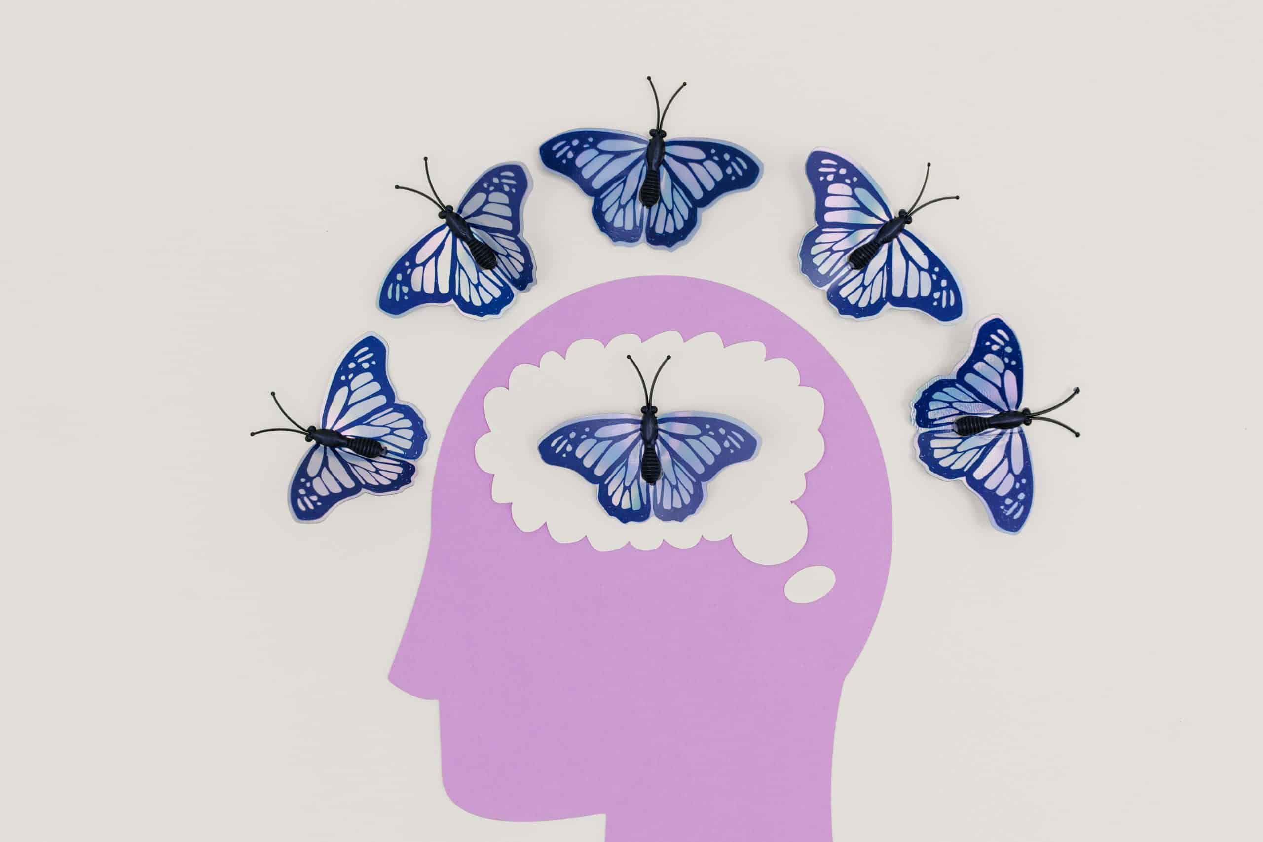 Creative illustration of butterflies symbolizing thoughts and transformation, fluttering over a brain silhouette—reflecting the journey of inner child healing and mental wellness.