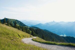 hiking lovers; a hiking trail on a grassy hill curving towards mountains in the distance