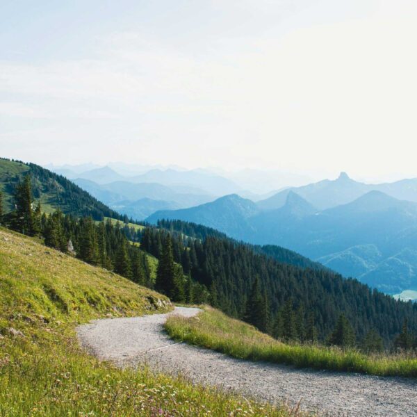 hiking lovers; a hiking trail on a grassy hill curving towards mountains in the distance