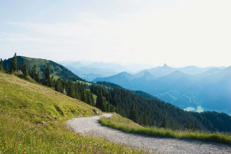 hiking lovers; a hiking trail on a grassy hill curving towards mountains in the distance