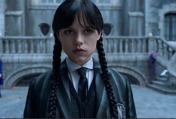 Jenna Ortega as Wednesday Addams, with braided pigtails and a serious expression, wearing her school uniform. Season 3