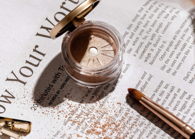 Close-up of a gold glitter eyeliner makeup brush applying sparkling gold powder, showcasing cosmetics and fashion beauty tools—perfect for beauty travel essentials. Image credit: AdoreBeautyNZ via Pixabay.
