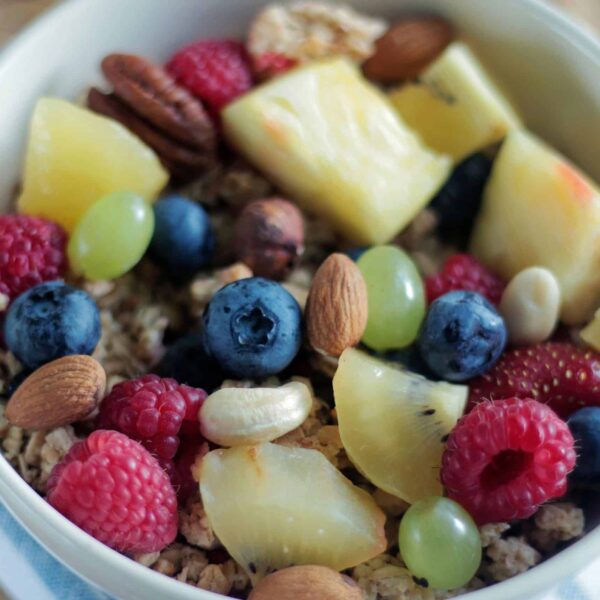 Close-up of a colorful muesli bowl with fresh berries, nuts, and pineapple. Contains superfoods