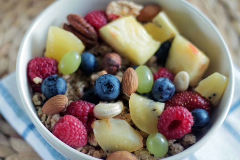 Close-up of a colorful muesli bowl with fresh berries, nuts, and pineapple. Contains superfoods