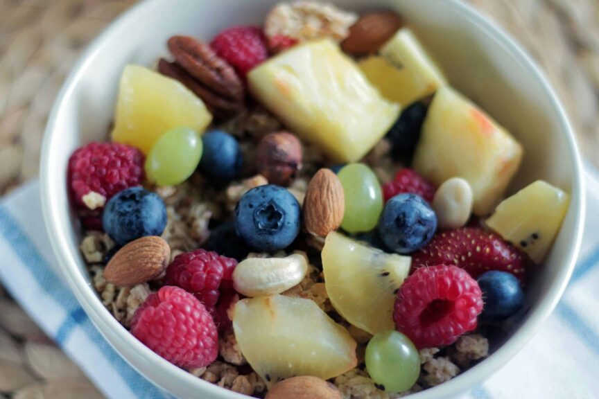 Close-up of a colorful muesli bowl with fresh berries, nuts, and pineapple. Contains superfoods