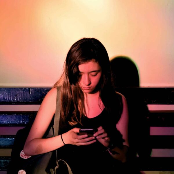 woman wearing black tank dress, using smartphone. Mindful news consumption