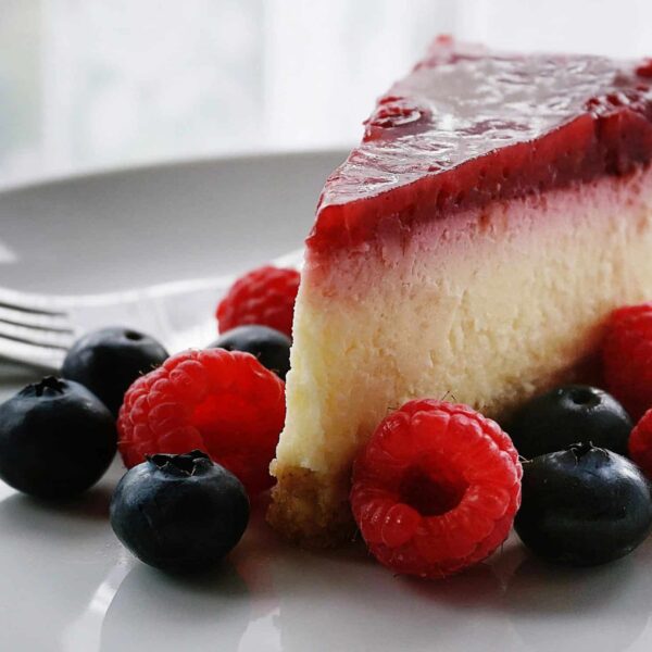 A tempting slice of cheesecake topped with berries, perfect for dessert lovers. National Cheesecake Day