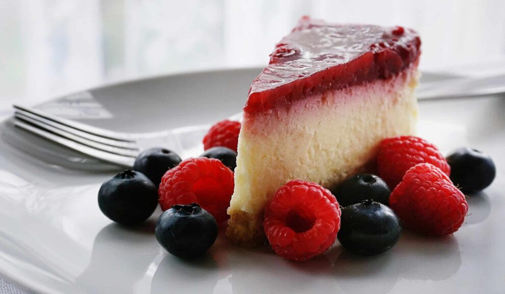 A tempting slice of cheesecake topped with berries, perfect for dessert lovers. National Cheesecake Day