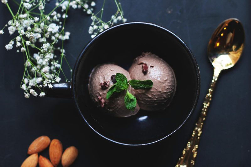 Bowl of rich chocolate dairy-free ice cream topped with mint leaves and sliced almonds, Image by Alisha Mishra via Pexels.