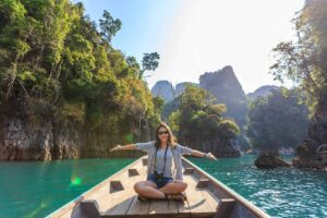 Asian woman relishing a serene boat journey through the lush karst landscape of Thailand's Khlong Sok. Ethical Tourism