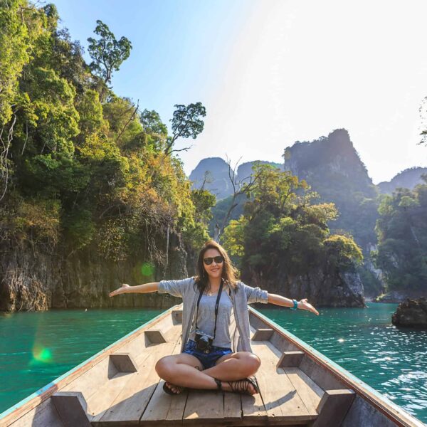 Asian woman relishing a serene boat journey through the lush karst landscape of Thailand's Khlong Sok. Ethical Tourism