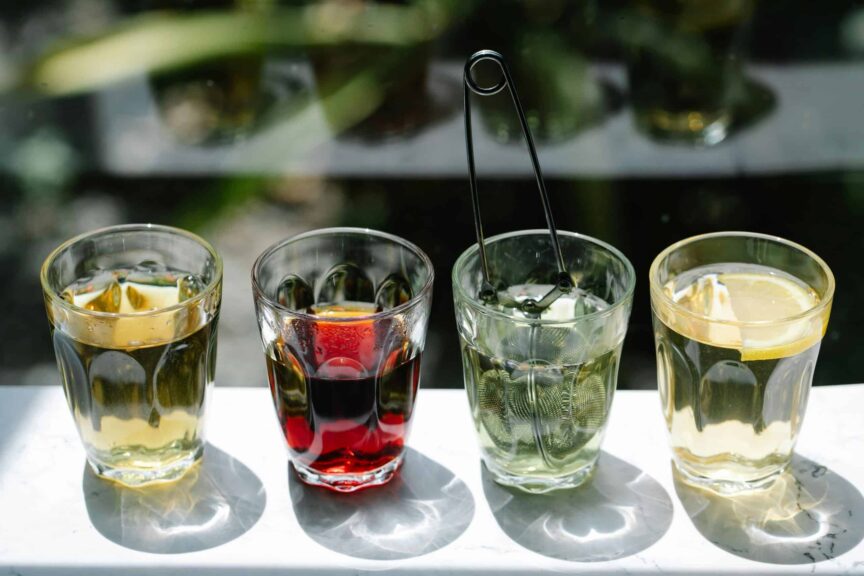 Four glasses of iced beverages in sunlight, showcasing colorful drink variety. summer drinks