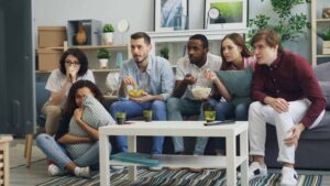 a group of people sitting on a couch in a living room / TV ratings