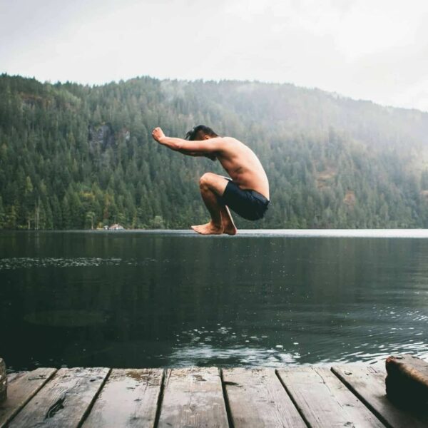 Man jumping into water from a dock
