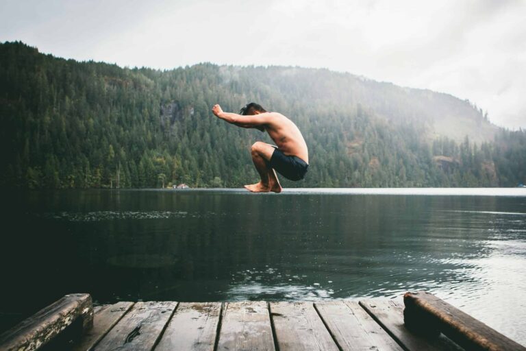 Man jumping into water from a dock