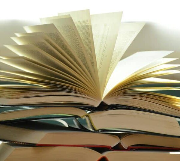 A close-up of a stack of open books with pages fanned out, capturing a study atmosphere.