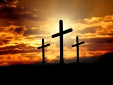 Three crosses silhouetted against a sunset sky, a symbol central to Christian beliefs