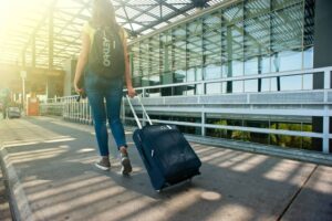 A woman walks with a suitcase outside an airport terminal, ready for travel with comfortable travel shoes.