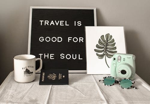 A travel-themed flat lay with a camera, coffee, and motivational quote.