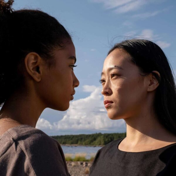 A close-up outdoor portrait of two women facing each other under a bright sky. toxic friendship